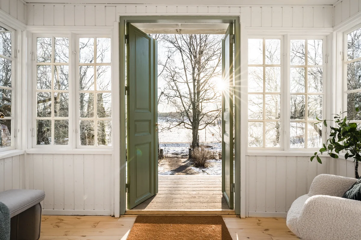 Renoverad inglasad veranda med gröna pardörrar